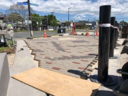 brick pavers laid in tauranga with a men in the background and some trees, fences and road and houses