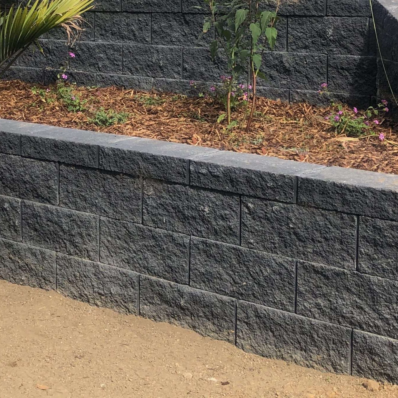 grey stone retaining wall with a garden